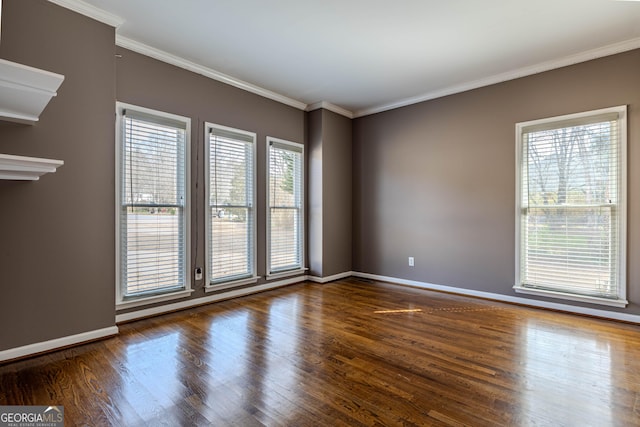 empty room with baseboards, wood finished floors, and crown molding