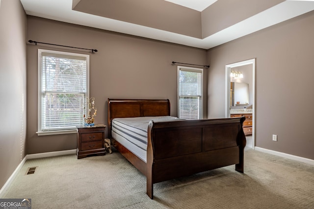 bedroom with light carpet, ensuite bath, visible vents, and baseboards