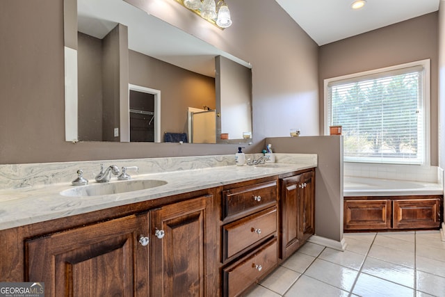 full bathroom featuring a garden tub, double vanity, tile patterned flooring, and a sink