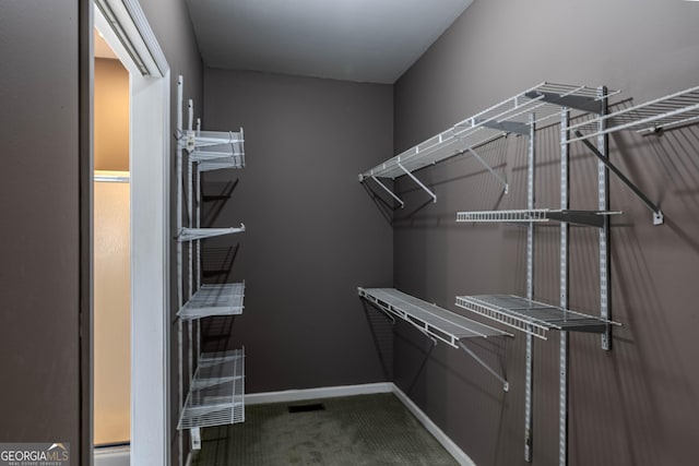 walk in closet featuring dark carpet