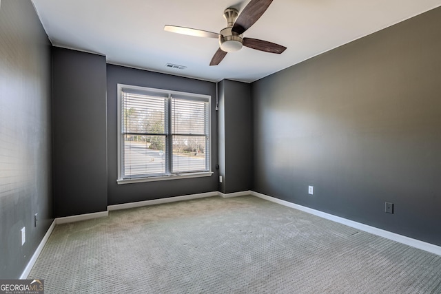 carpeted empty room featuring baseboards, visible vents, and a ceiling fan