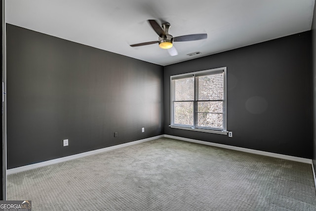 spare room with carpet floors, visible vents, baseboards, and a ceiling fan