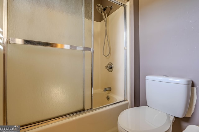 bathroom with toilet and bath / shower combo with glass door