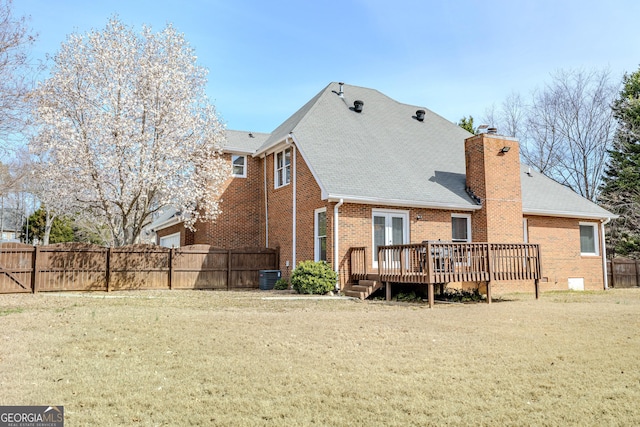 rear view of property featuring a wooden deck, a chimney, fence, a yard, and brick siding