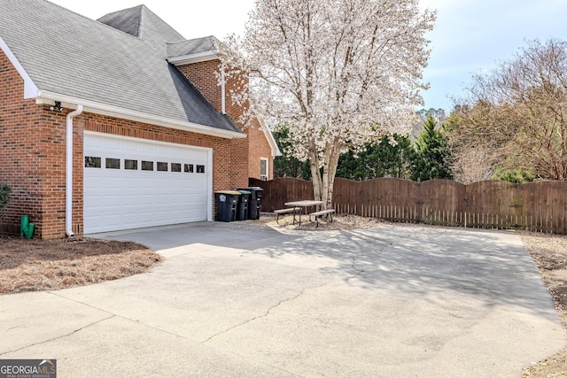 view of side of home featuring driveway, a gate, fence, and brick siding