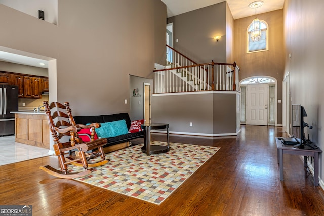 living area featuring wood-type flooring, a high ceiling, stairway, and baseboards