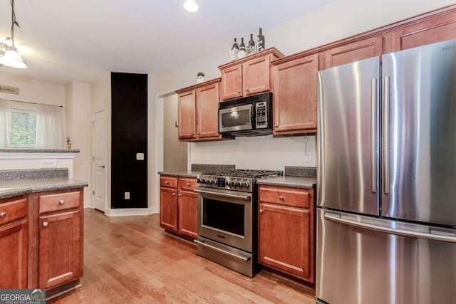 kitchen featuring light wood-type flooring, dark countertops, and stainless steel appliances