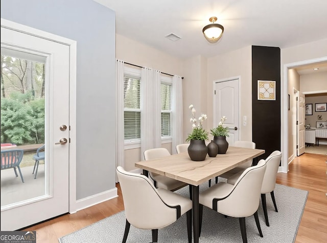 dining space featuring light wood-style floors, baseboards, and visible vents