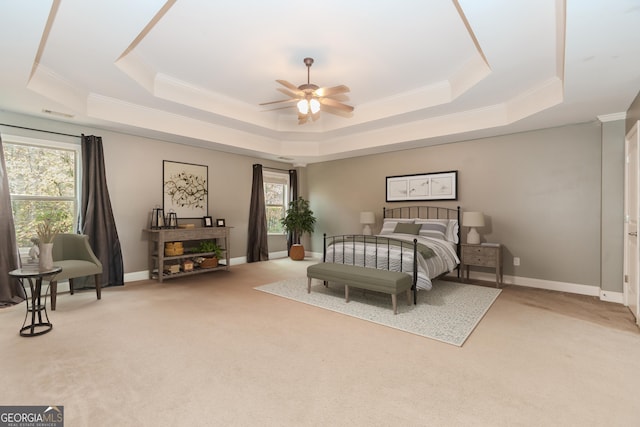 carpeted bedroom featuring multiple windows, a tray ceiling, and ornamental molding