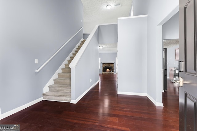 foyer with a textured ceiling, hardwood / wood-style floors, a fireplace, and baseboards