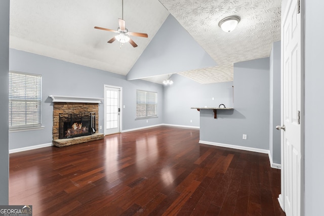 unfurnished living room featuring a ceiling fan, a stone fireplace, baseboards, and wood finished floors