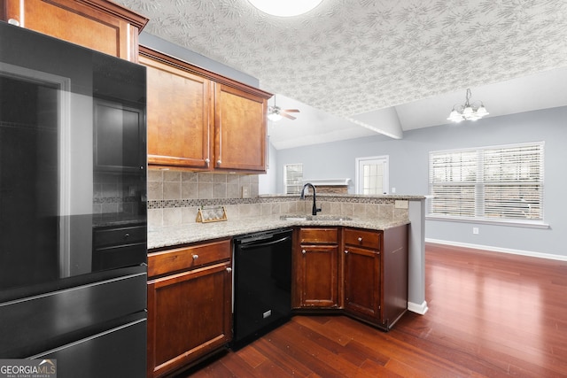 kitchen with refrigerator, black dishwasher, tasteful backsplash, a sink, and a peninsula