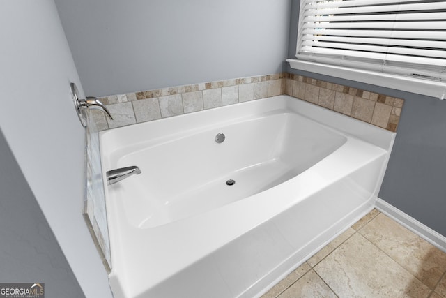 full bath featuring tile patterned flooring, a garden tub, and baseboards