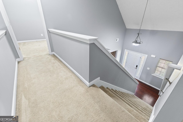 stairway with carpet floors, high vaulted ceiling, and baseboards