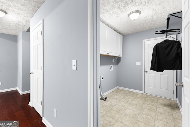 clothes washing area featuring cabinet space, baseboards, washer hookup, and a textured ceiling