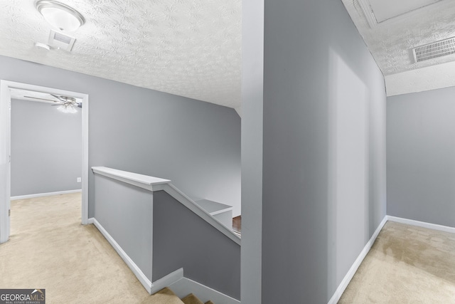 corridor featuring baseboards, visible vents, carpet flooring, and an upstairs landing