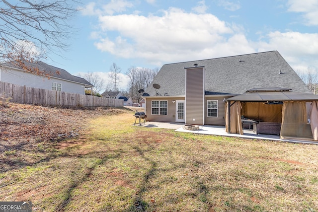 back of property with fence, a gazebo, a lawn, a chimney, and a patio area