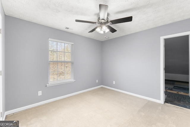 empty room with carpet, a textured ceiling, visible vents, and baseboards