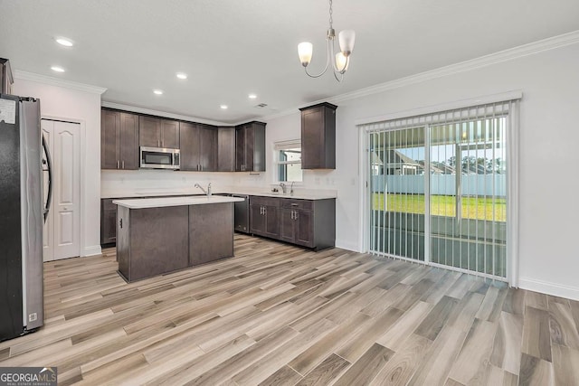 137 Walnut Way, Kingsland, GA 31548 - kitchen featuring stainless steel appliances, a sink, dark brown cabinets, crown molding, and light wood-style floors