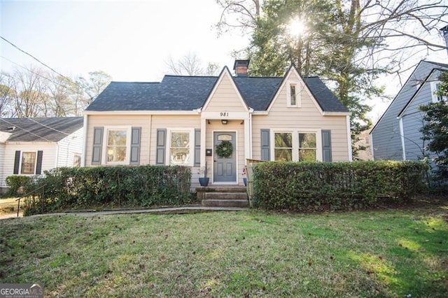 view of front of property with a chimney, a front lawn, and roof with shingles