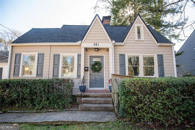 bungalow-style house featuring roof with shingles and a chimney