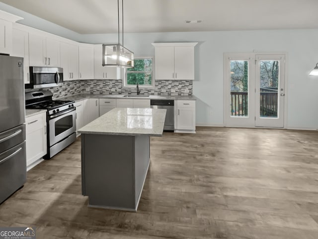 kitchen with a center island, stainless steel appliances, backsplash, a sink, and wood finished floors