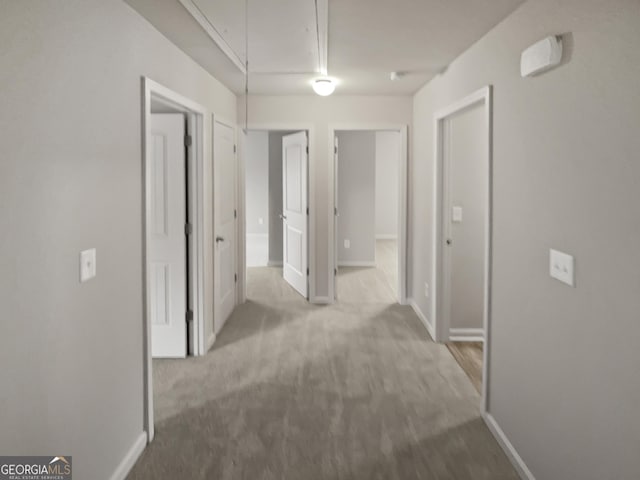 corridor featuring attic access, carpet floors, and baseboards