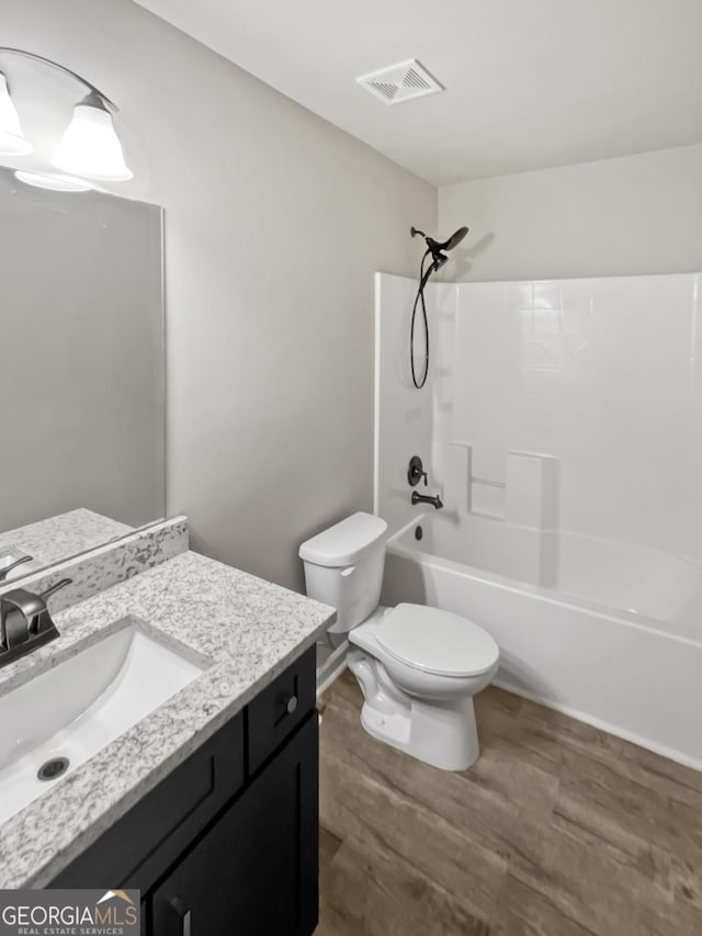 full bathroom with toilet, wood finished floors, vanity, visible vents, and  shower combination