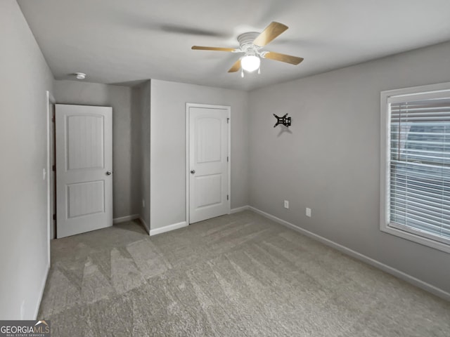 unfurnished bedroom with carpet, multiple windows, ceiling fan, and baseboards