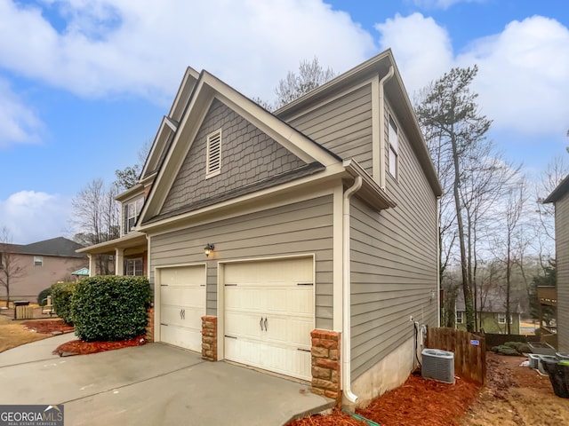 view of side of home featuring a garage, central AC, and concrete driveway