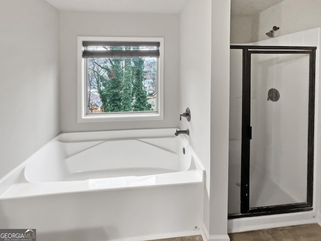 bathroom featuring a garden tub and a shower stall