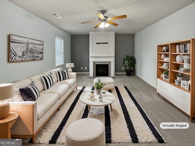 carpeted living room with a large fireplace, ceiling fan, visible vents, and baseboards