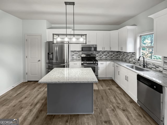 kitchen with stainless steel appliances, tasteful backsplash, a sink, and a center island