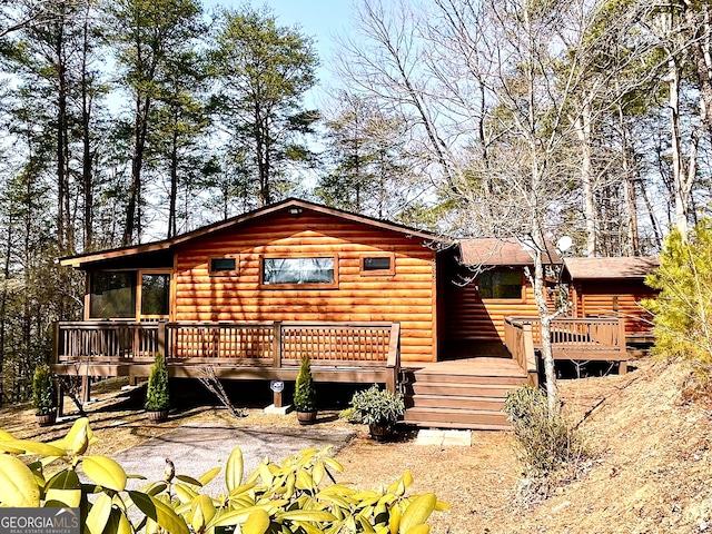 view of front of home featuring log veneer siding and a wooden deck