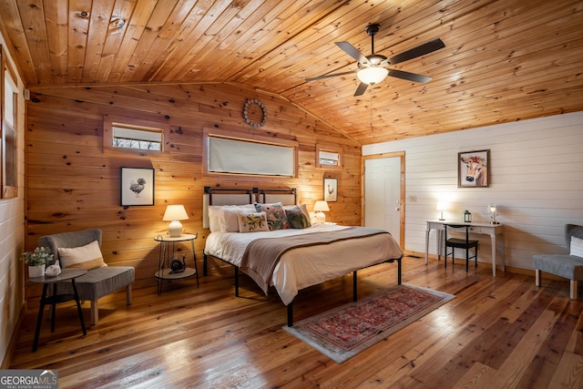 bedroom featuring wood walls, hardwood / wood-style floors, and vaulted ceiling