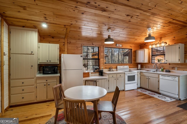 kitchen with wood walls, white appliances, light countertops, and a sink