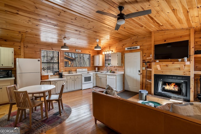 living room featuring vaulted ceiling, wooden walls, light wood-style flooring, a ceiling fan, and wood ceiling