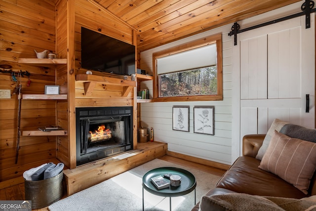 living room featuring a warm lit fireplace, wood walls, wooden ceiling, and a barn door