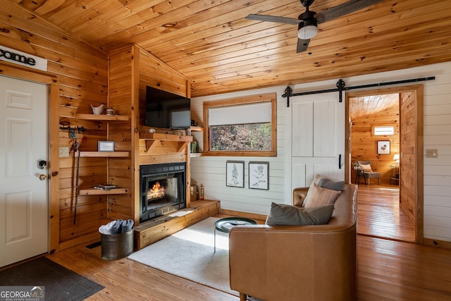 living area with a ceiling fan, vaulted ceiling, wooden ceiling, wood walls, and wood-type flooring