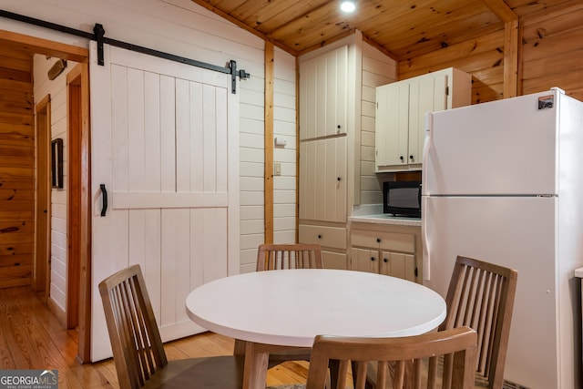 dining space with wooden walls, a barn door, and wood ceiling