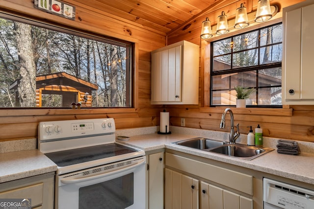 kitchen with light countertops, wood walls, a sink, and white appliances