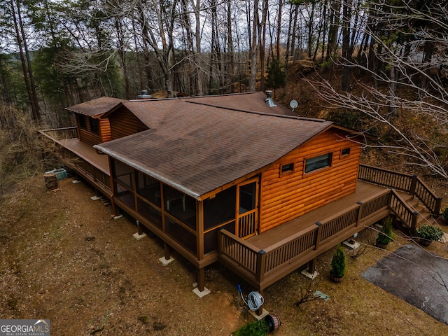 exterior space with a deck, a shingled roof, log veneer siding, and stairs