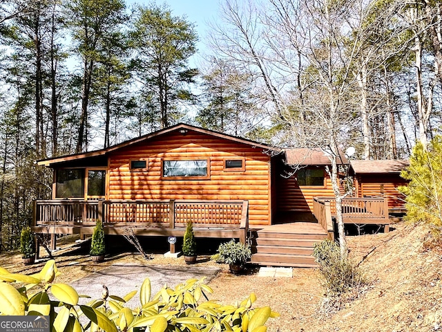 view of front of home with a wooden deck and log veneer siding