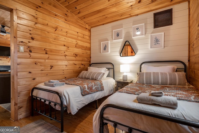 bedroom with wooden walls, visible vents, wooden ceiling, and wood finished floors