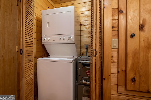 laundry area with laundry area, wood walls, and stacked washer / drying machine
