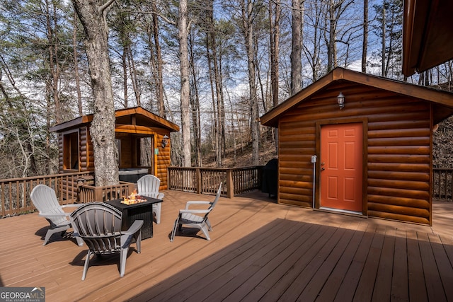 wooden terrace with a fire pit and an outdoor structure
