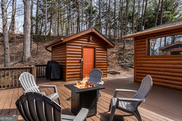 deck featuring area for grilling, a fire pit, and an outdoor structure