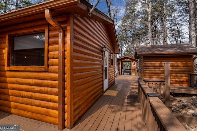 exterior space with a shingled roof, a wooden deck, and faux log siding