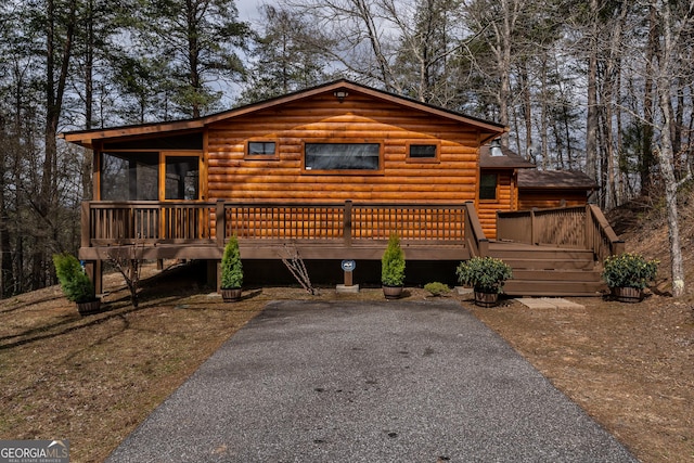 cabin with a deck and log veneer siding