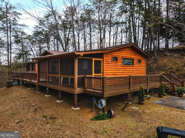 rear view of property featuring a deck, a sunroom, and log veneer siding